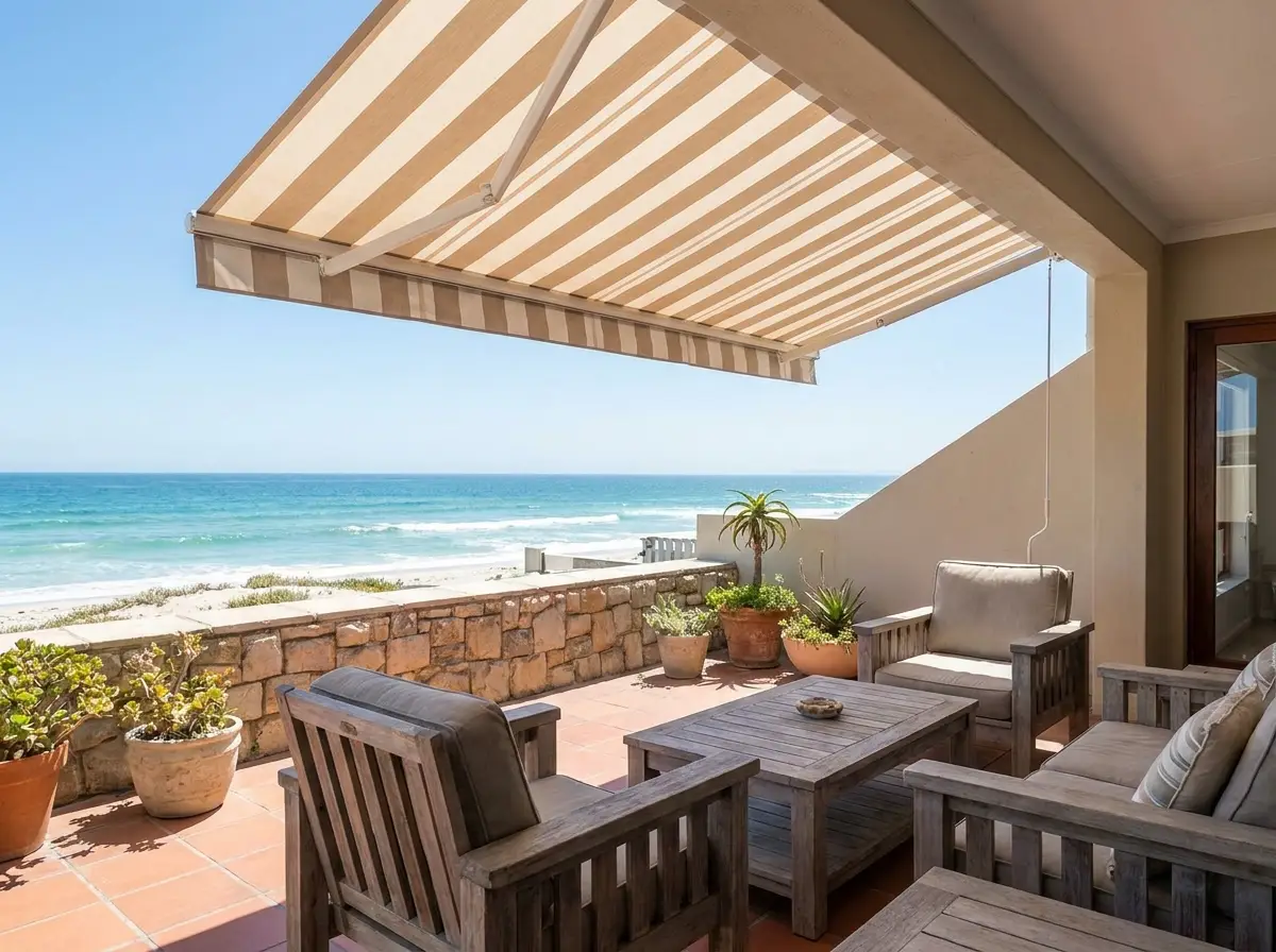 Folding-arm awning shading a beachfront patio overlooking the ocean, Strand